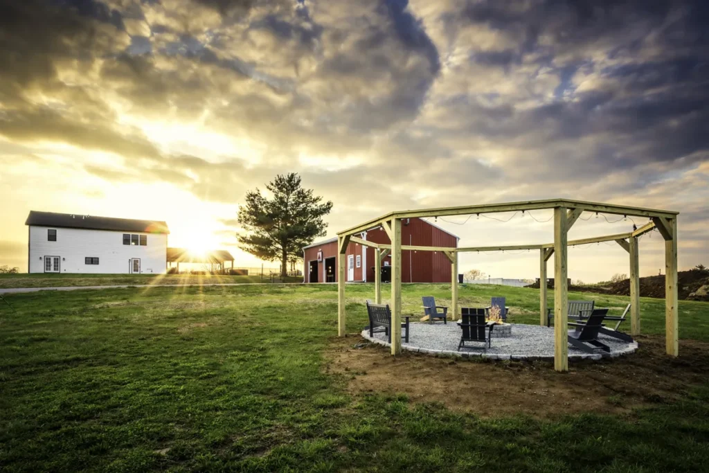 Fire pit beneath the pergola with the Farmhouse and Game Barn beyond